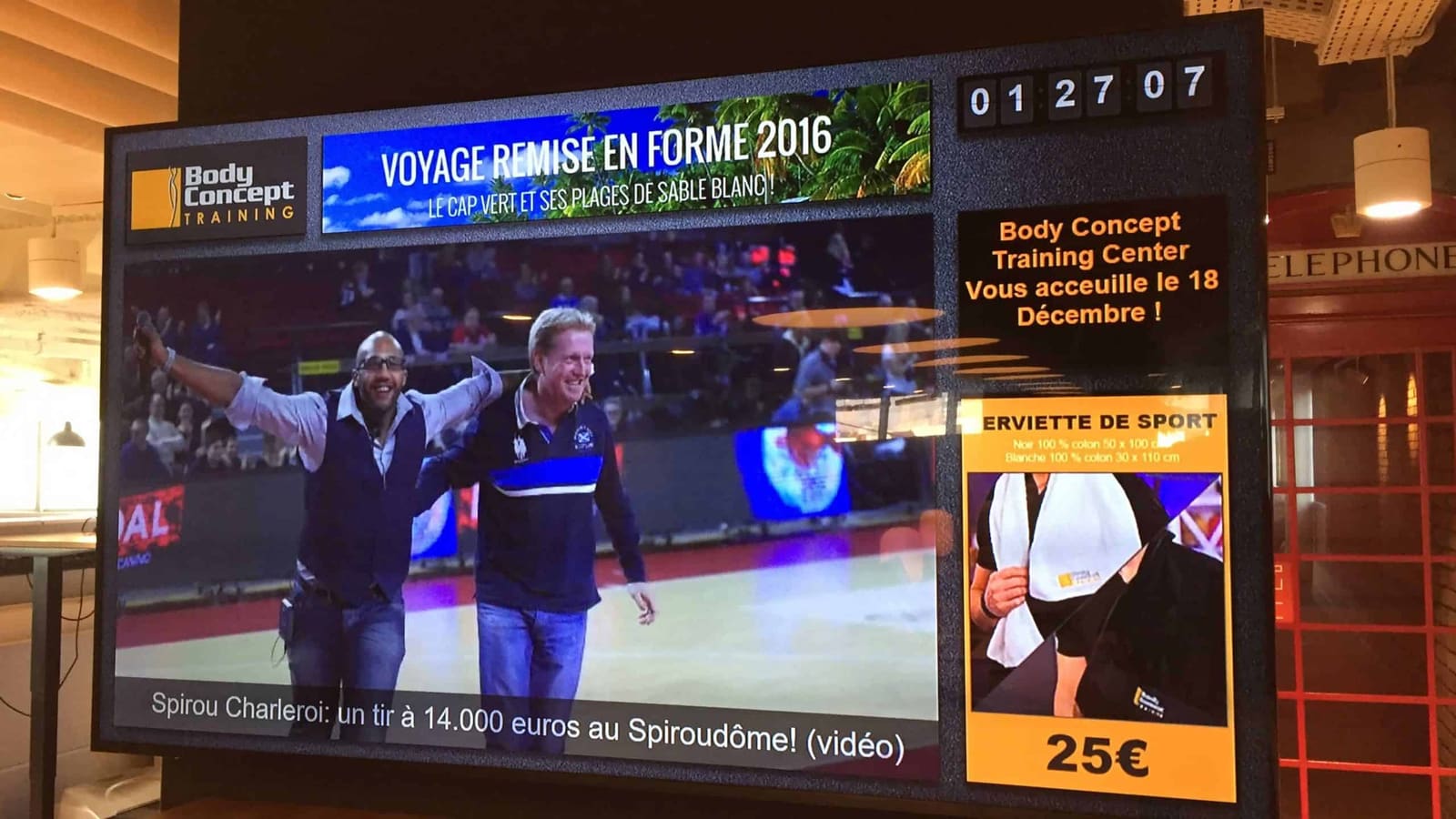 Body Concept Training, Belgium: a multi-zone gym screen with news video, an offer and the clock