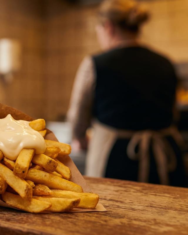 A paper cone of Belgian fries with mayonnaise
